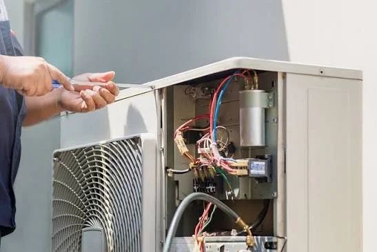Technician troubleshooting outdoor condenser unit electrical components