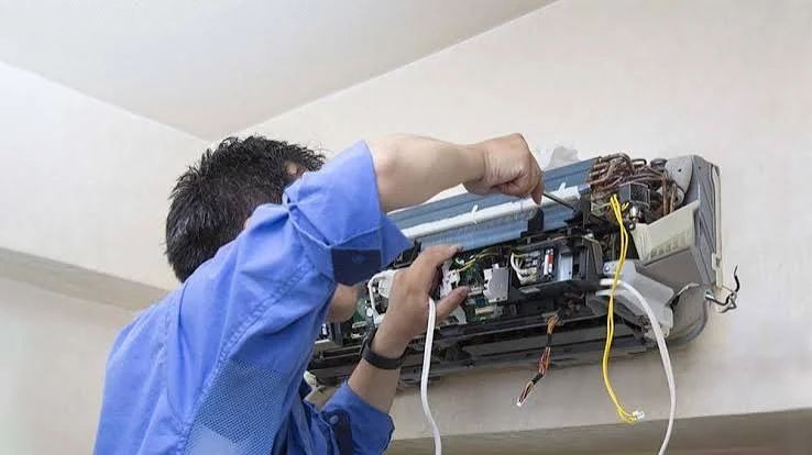 HVAC technician inspecting internal air handler and ductwork wiring connections